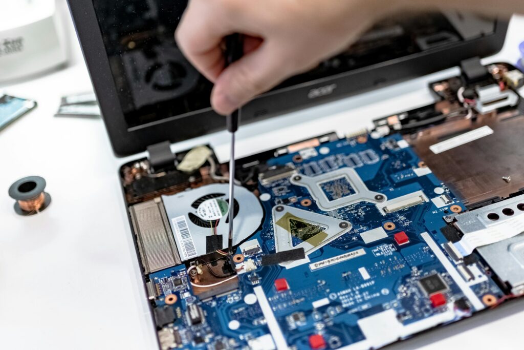 pexels-photo-7639373-7639373 Hand repairing a laptop motherboard with a screwdriver, highlighting tech maintenance.